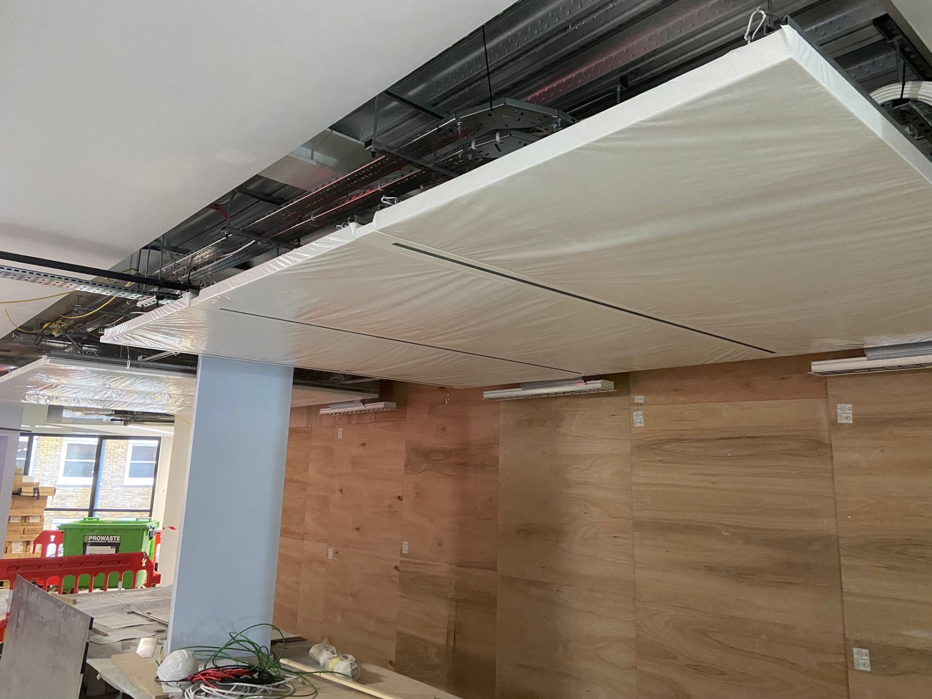 SEAM ceiling raft mid-install at BW New HQ, protective sheeting still in place over the finished panels