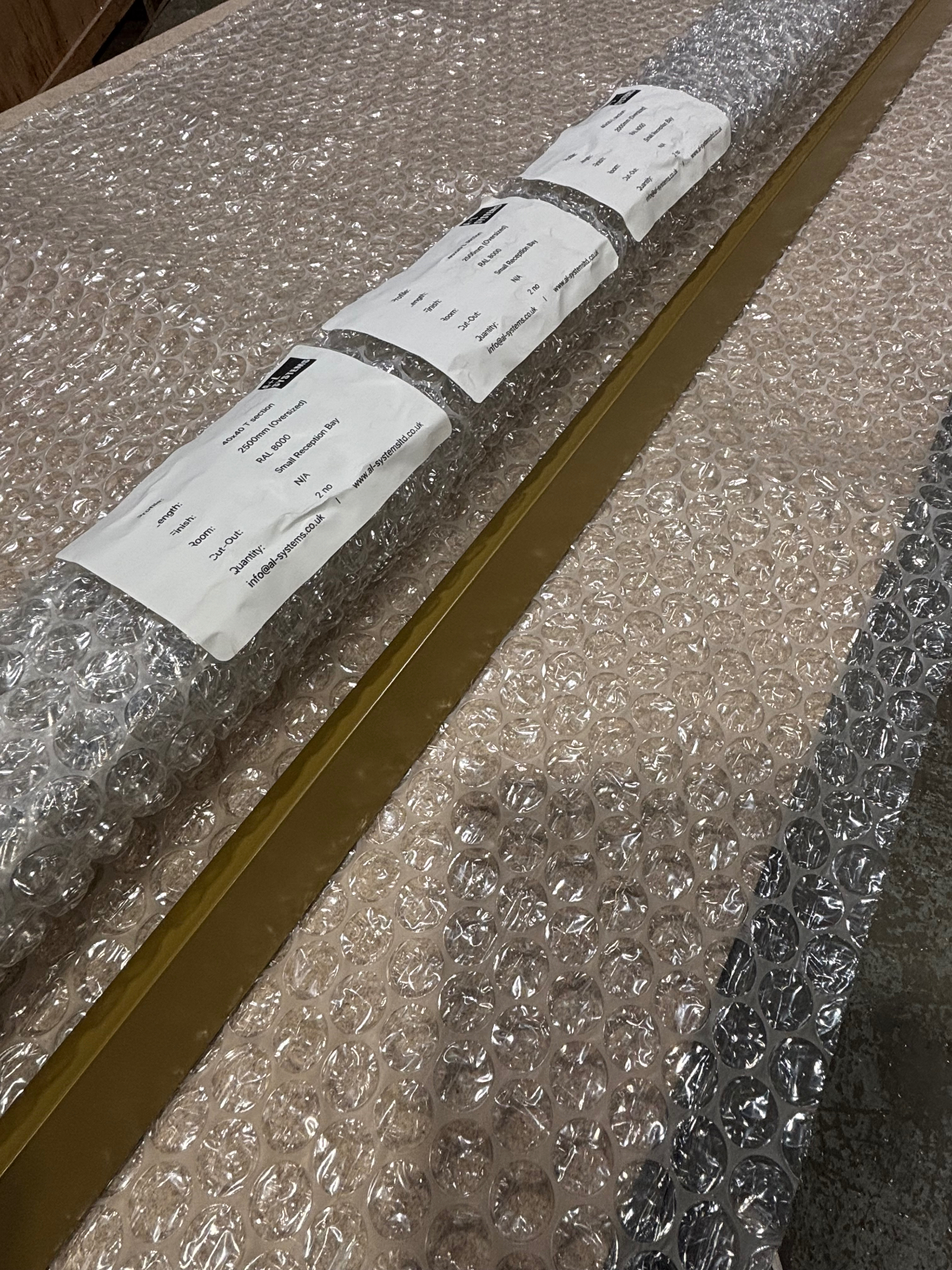 Bespoke RAL 8000 T-section ceiling grid profiles wrapped and labelled for the 75 KWS small reception bay in the A&L workshop