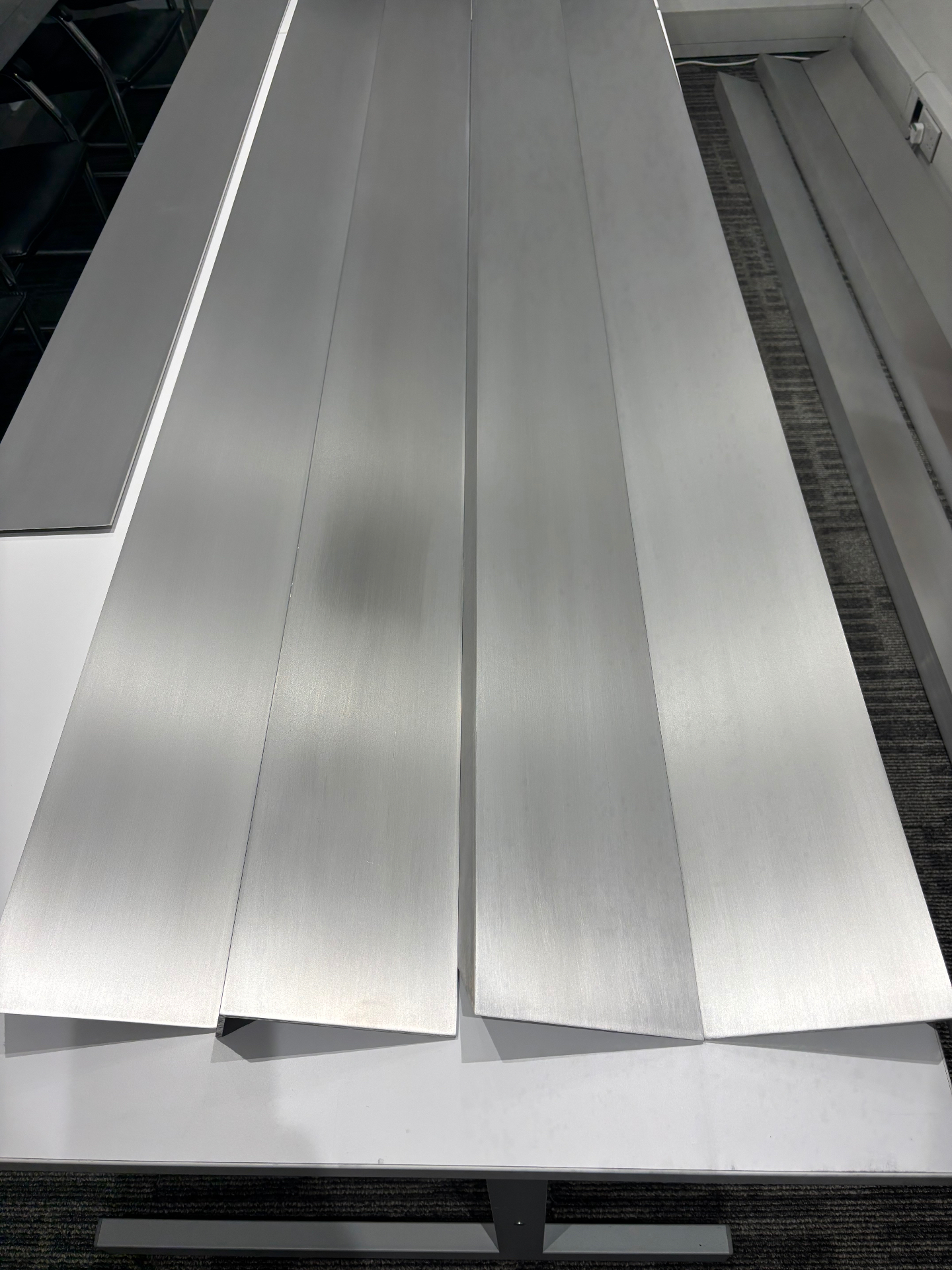 Batch of brushed aluminium SEAM channel profiles laid out for inspection in the A&L workshop