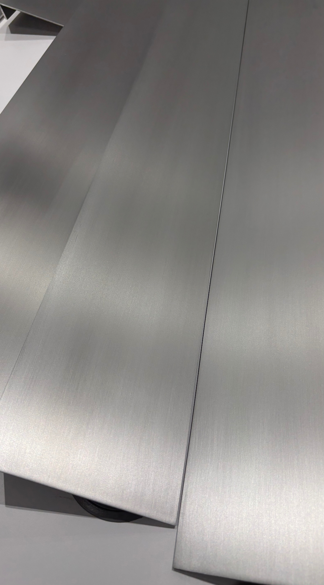 Detail of hand-brushed aluminium SEAM profiles showing the linear grain finish