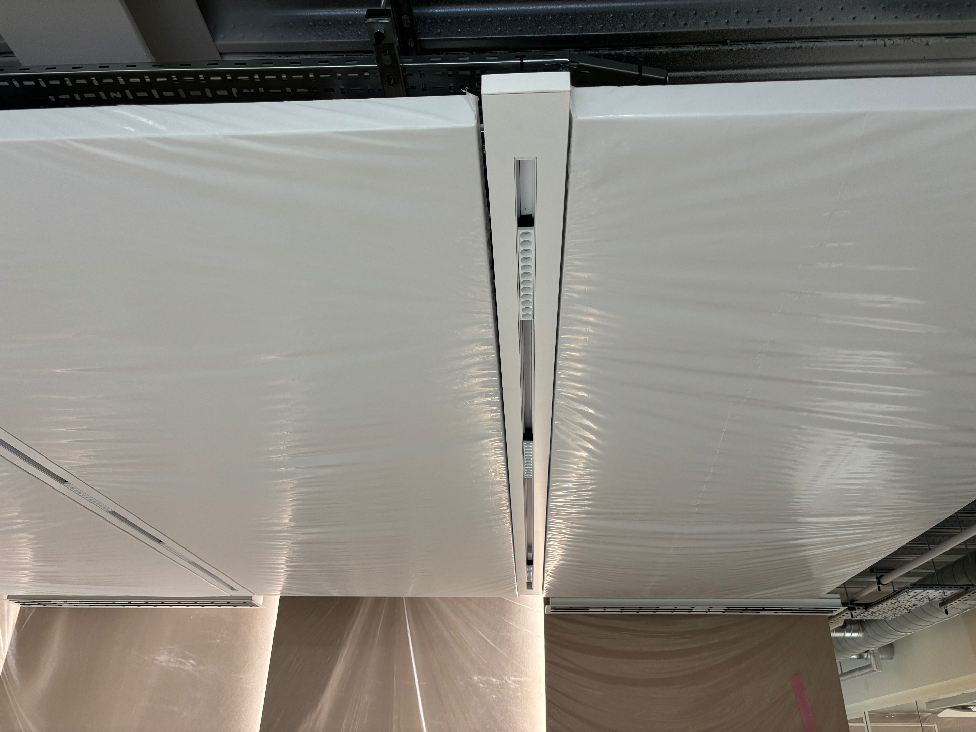 SEAM 100mm flush channel with integrated linear light being installed between protected ceiling bays on site at BW New HQ