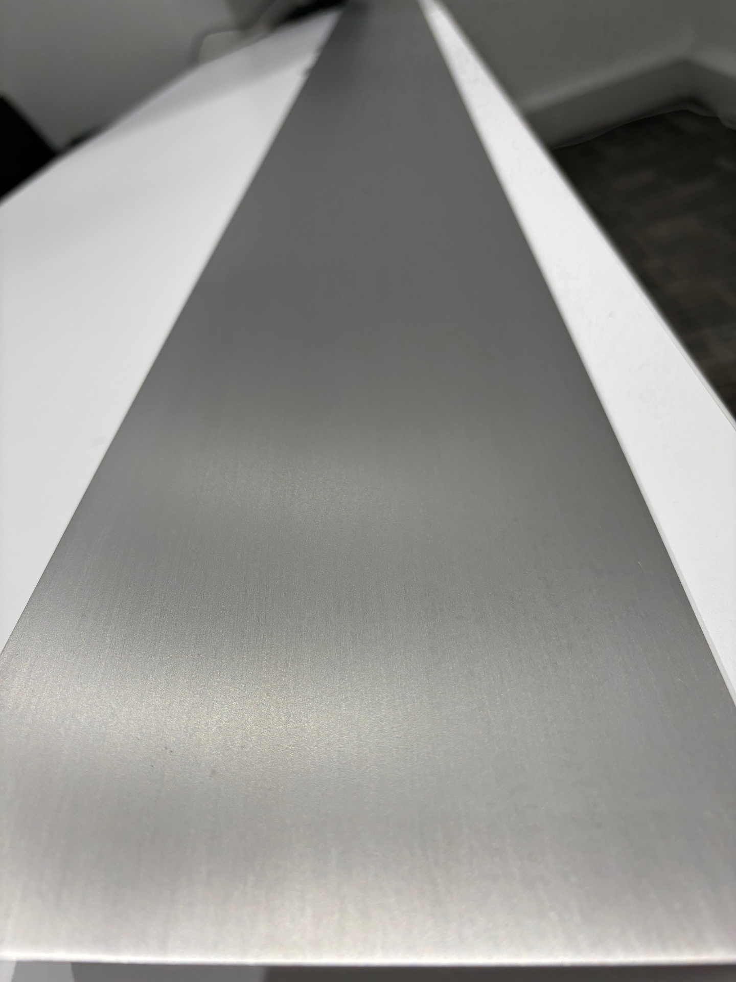 Hand-brushed raw aluminium SEAM trim profile in the A&L workshop, close-up of the finish